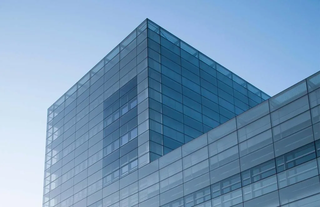 A modern glass building reflects the clear blue sky