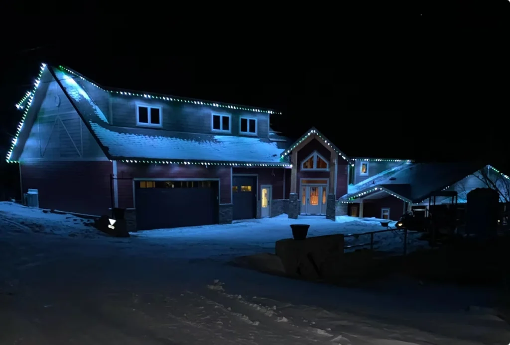 Gemstone lights illuminate a cozy house in a snowy night landscape