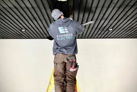 Worker installing lighting above a hot tub wiring setup using a ladder