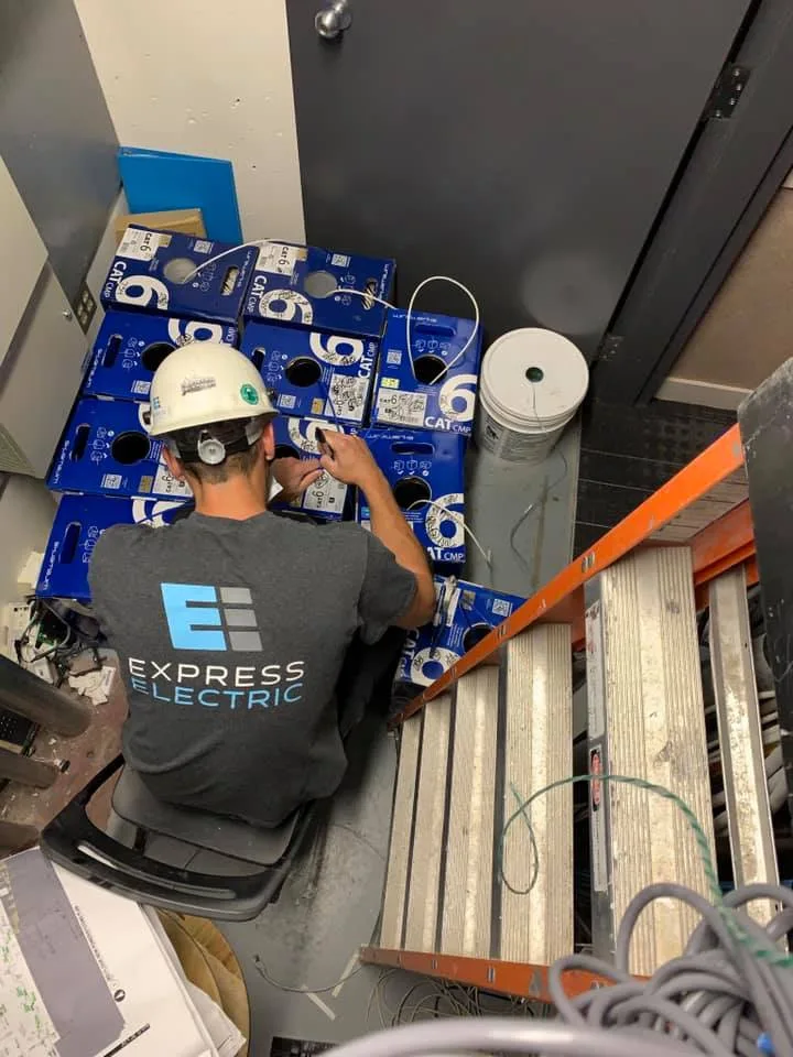 Electrician in cathedral repairs equipment while seated on stairs among tools and boxes